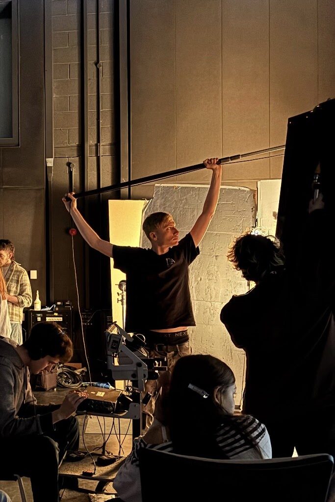 Daniel Friend operating a boom microphone on set